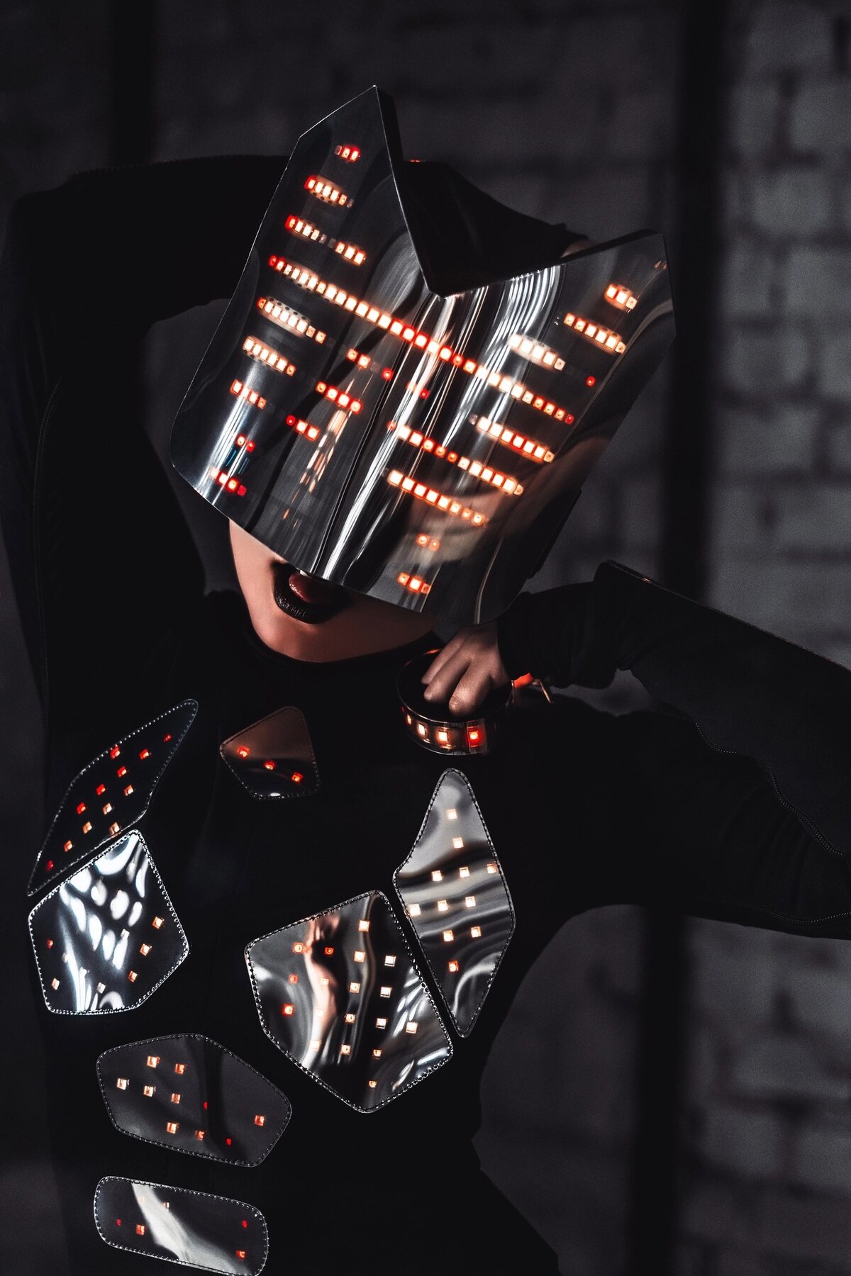 Stage costume with an angular mirrored helmet and faceted chest panels lit by red LEDs
