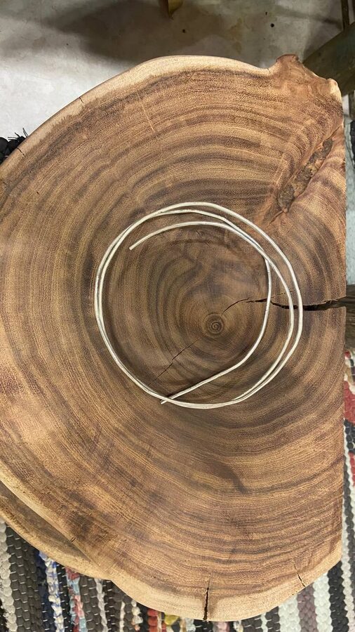 Coil of hammered round silver wire on a live-edge wood slab