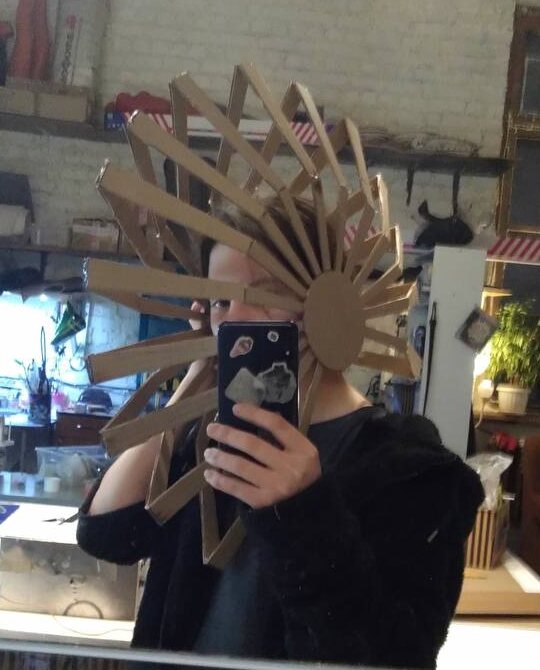 Cardboard mock-up of the fan headdress, tried on in the workshop mirror