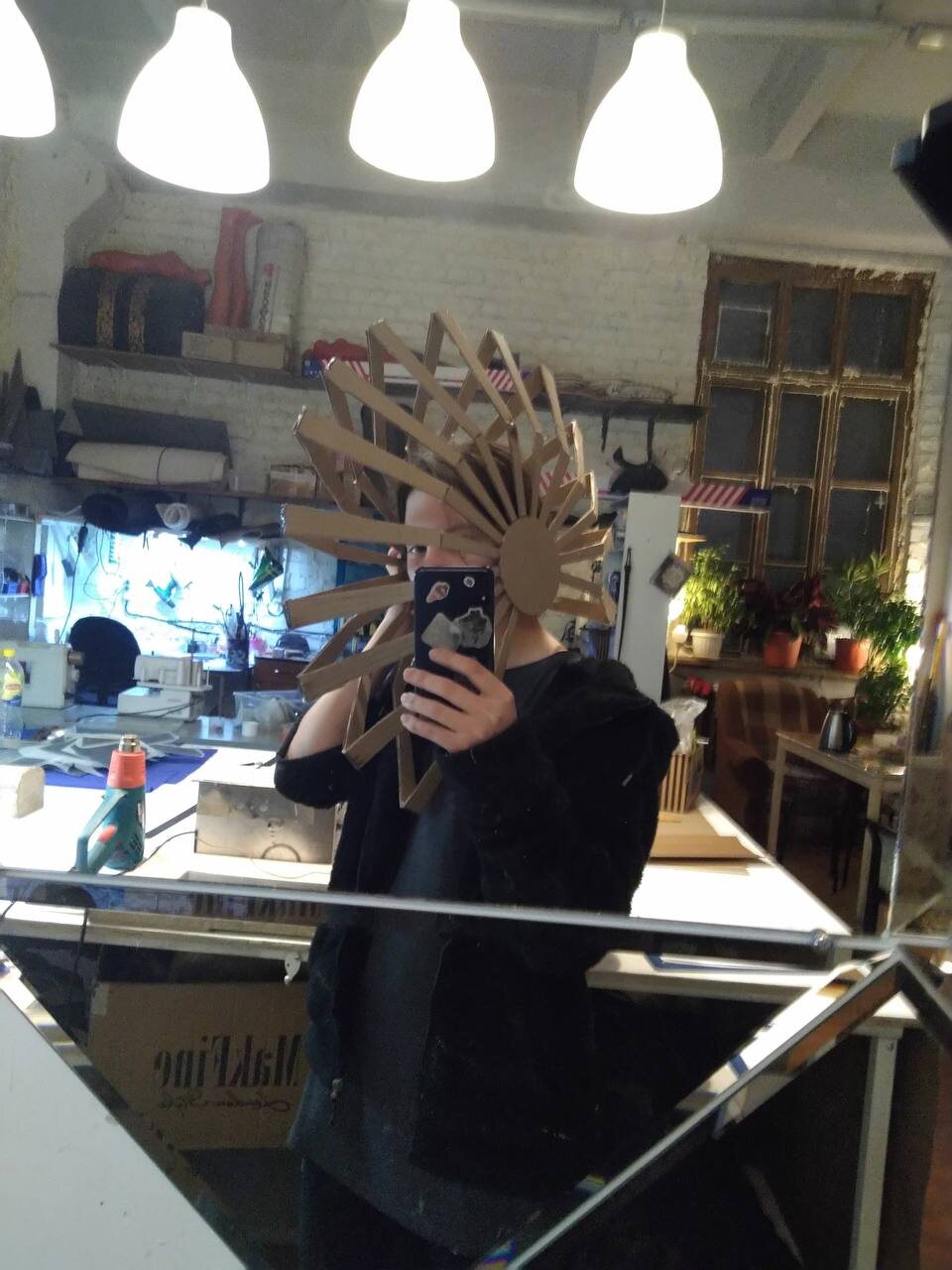 Cardboard mock-up of the fan headdress, tried on in the workshop mirror